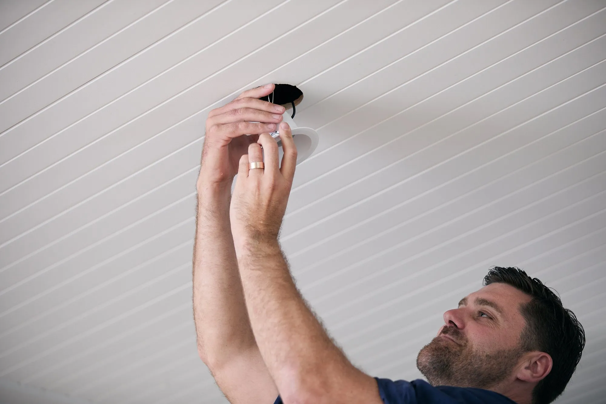 Anthony Kitson fitting a downlight into a timber ceiling