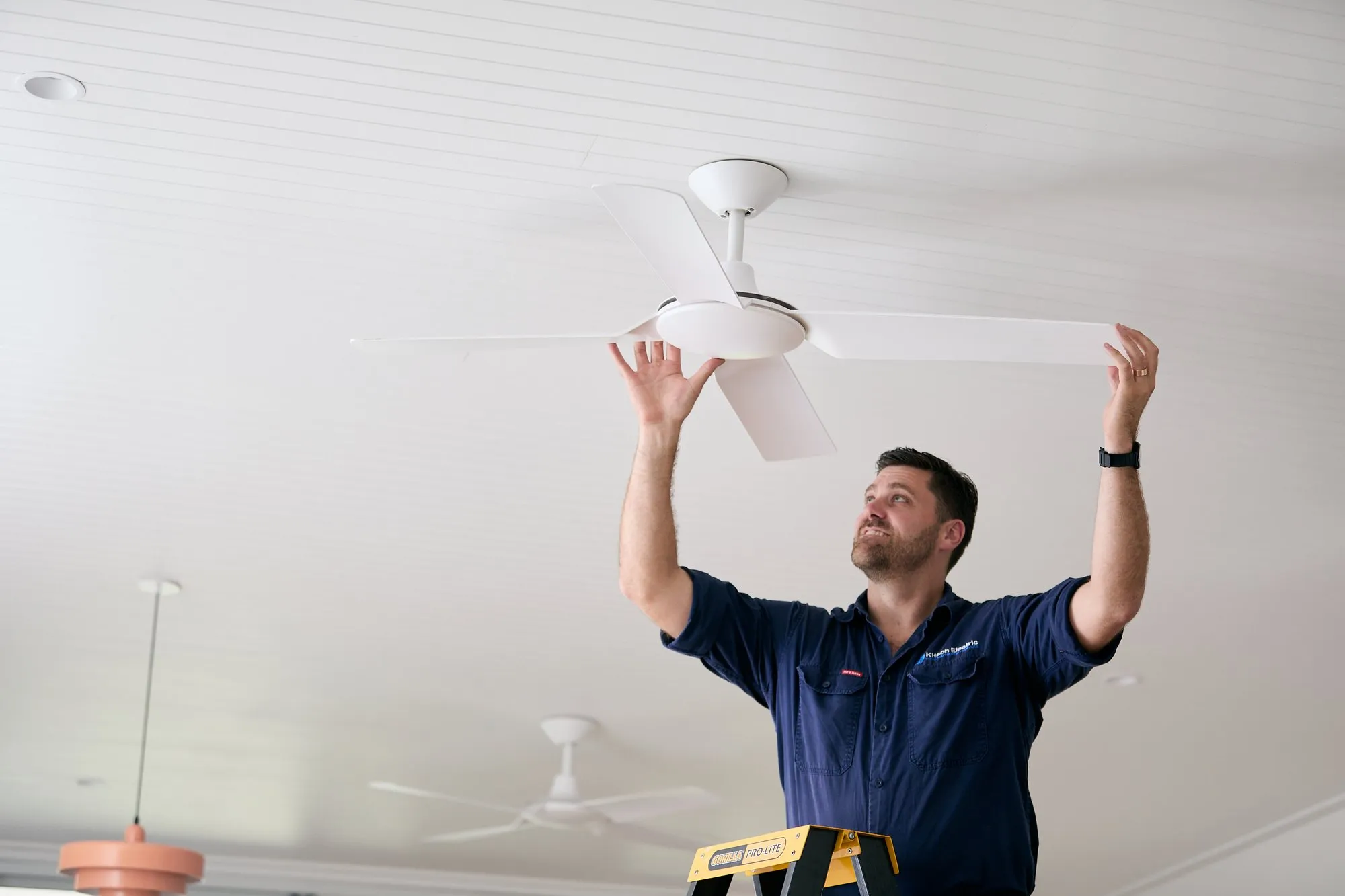 Anthony Kitson holding a ceiling fan in place