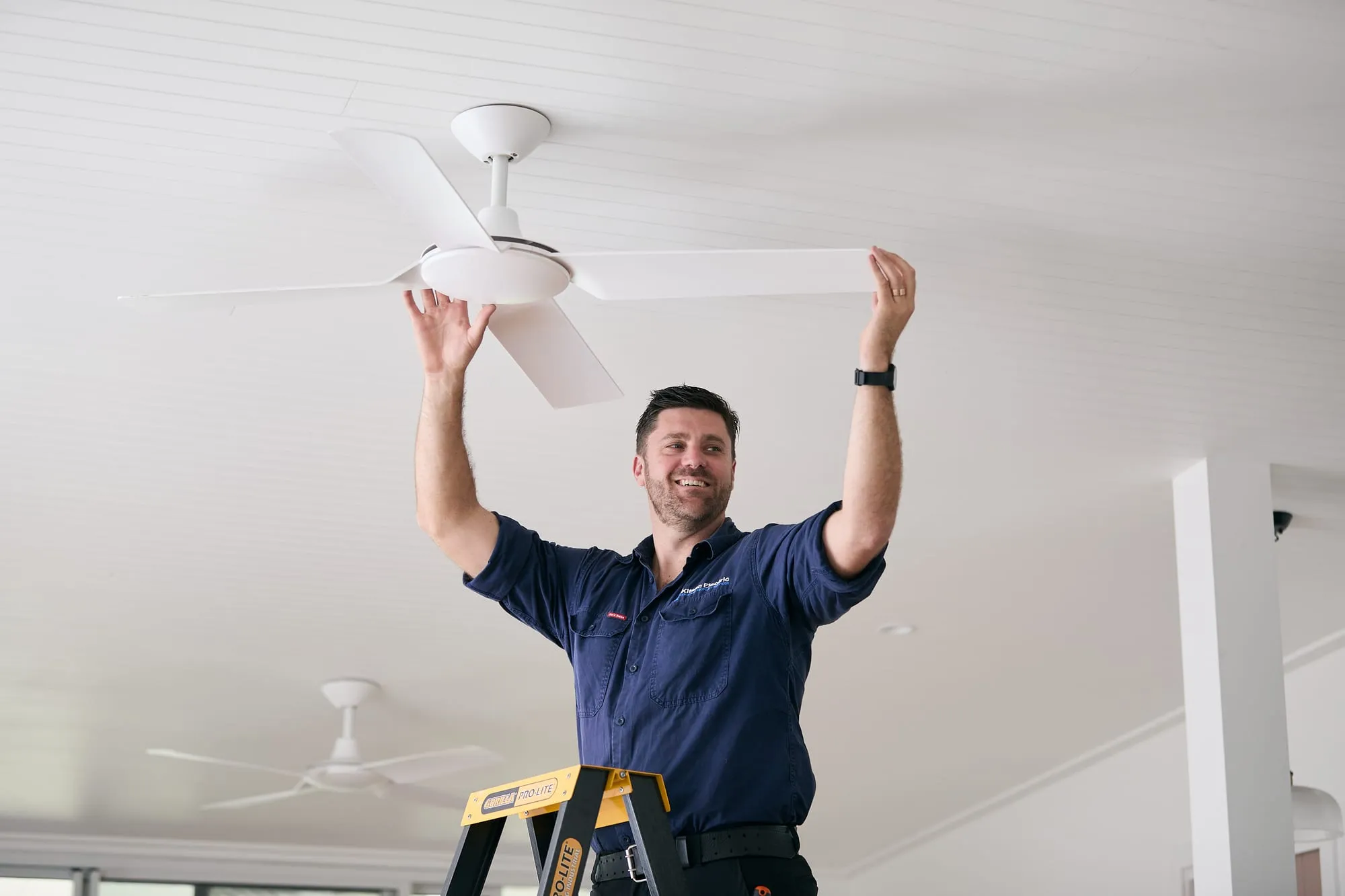 Anthony Kitson installing a ceiling fan in a Newcastle home