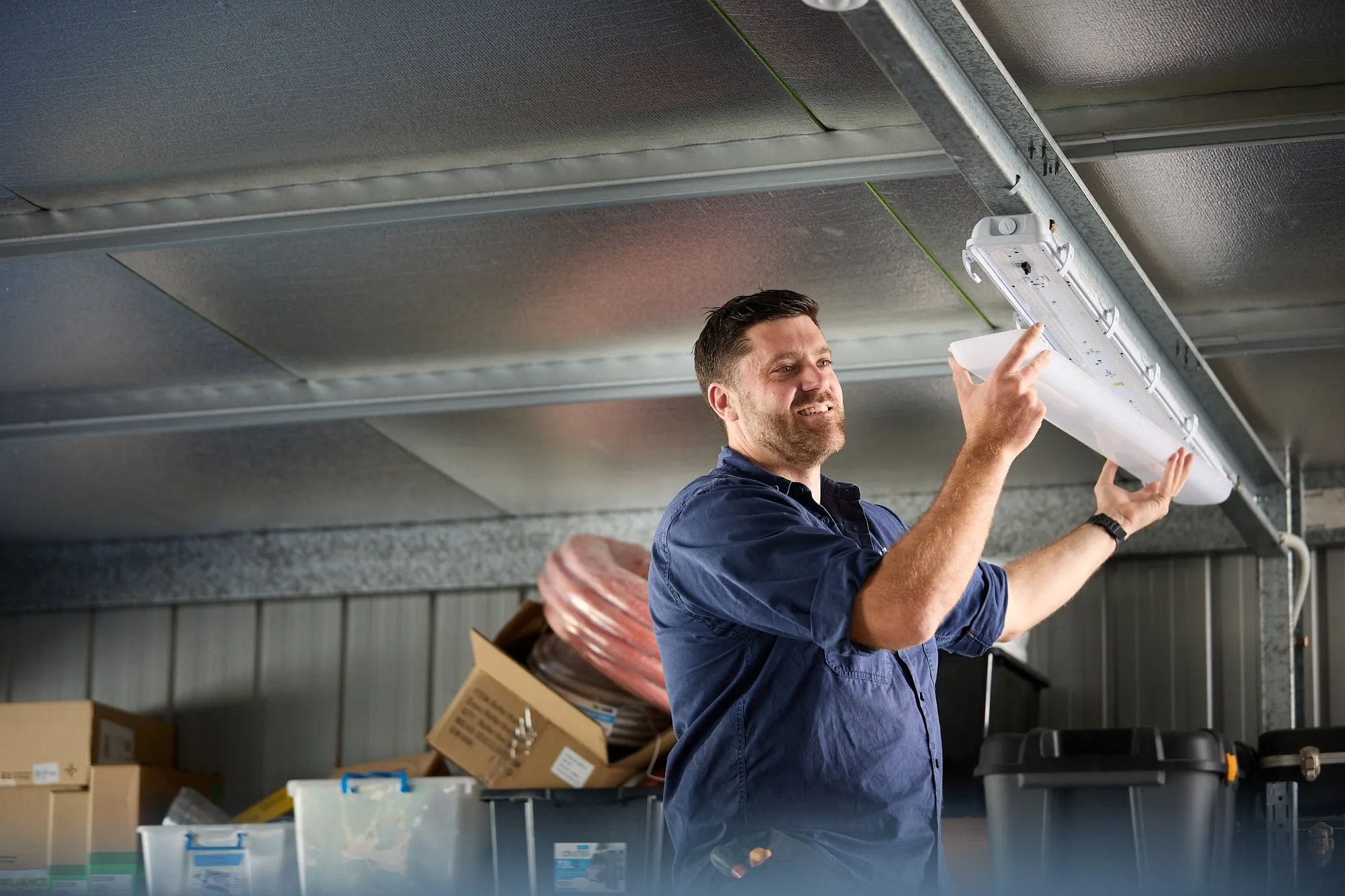 Anthony Kitson installing LED batten lighting in a Newcastle shed