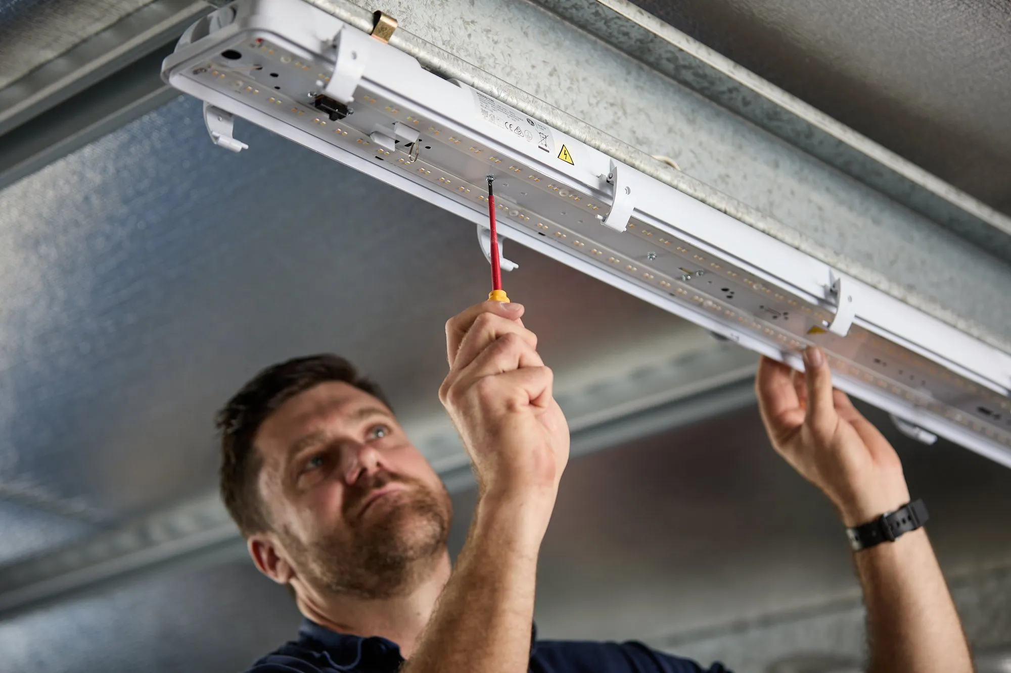 Anthony Kitson fixing an LED batten light, close up