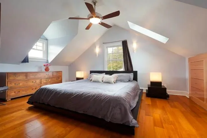 A ceiling fan with light in an attic bedroom