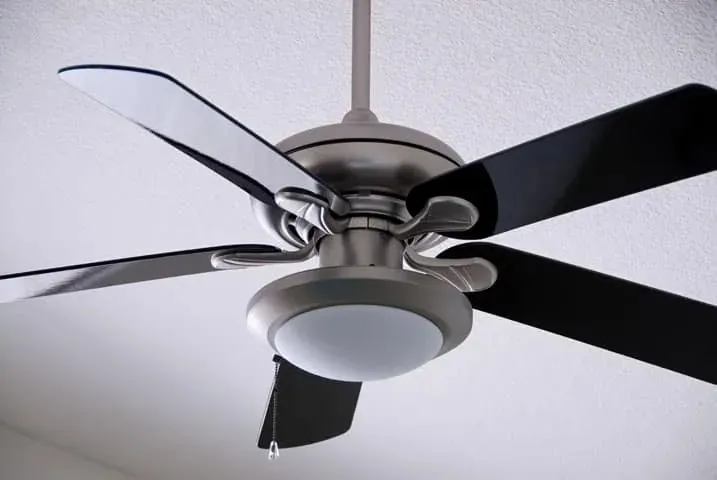 A ceiling fan with black blades and a light kit