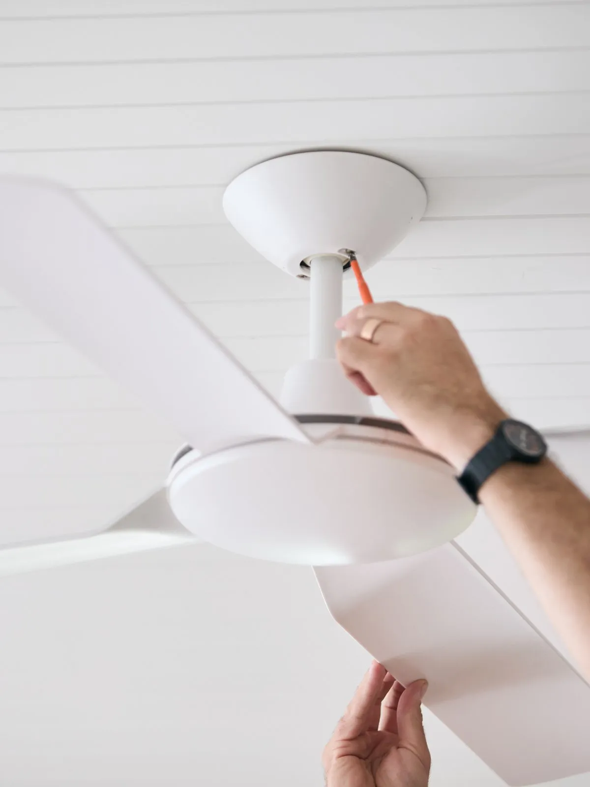 A white ceiling fan light being fitted, seen from below
