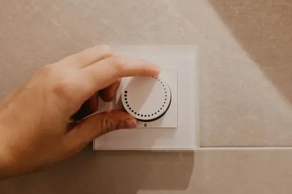 A hand turning a dimmer switch