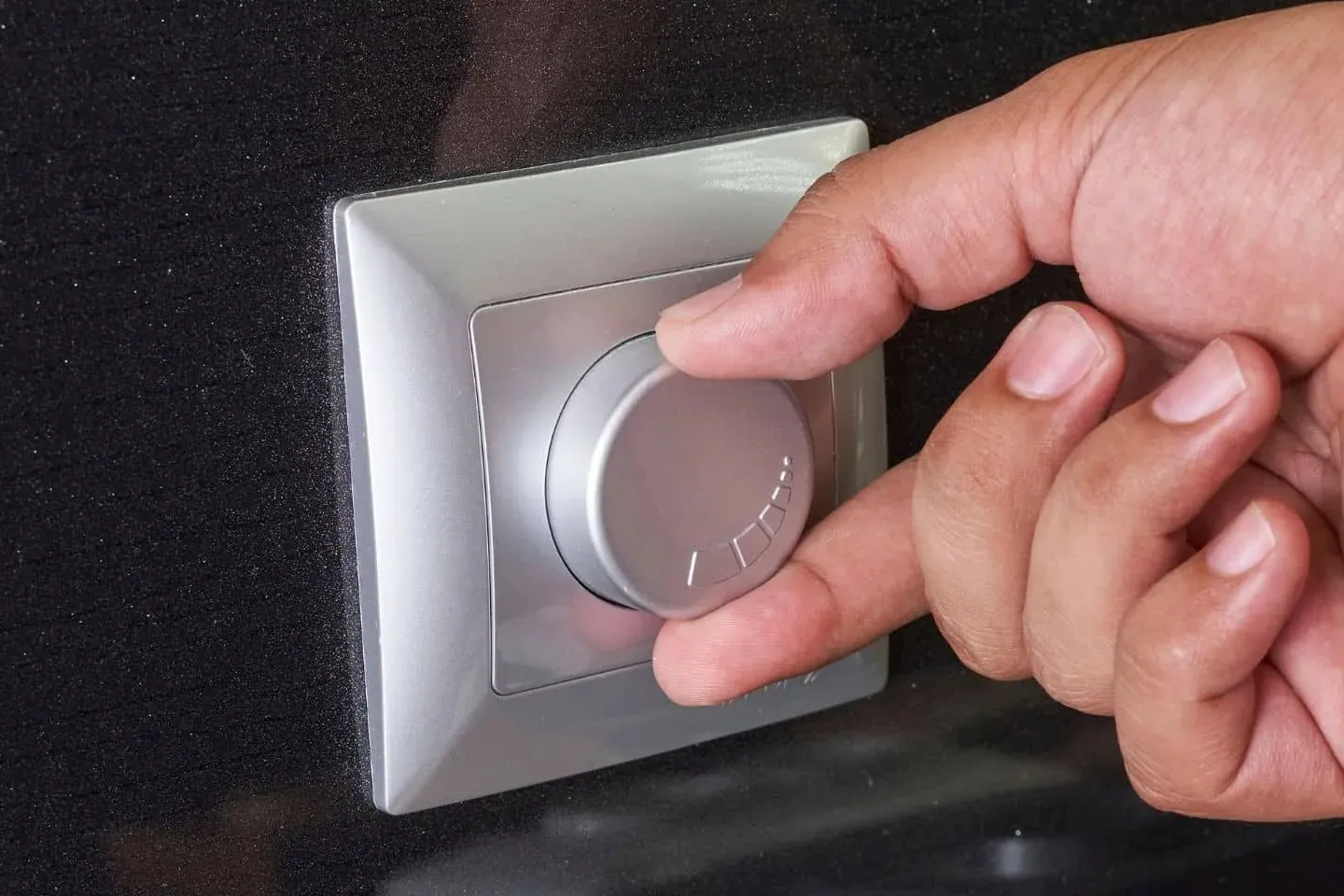 A hand turning a dimmer