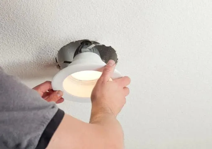 A downlight being pushed into the ceiling