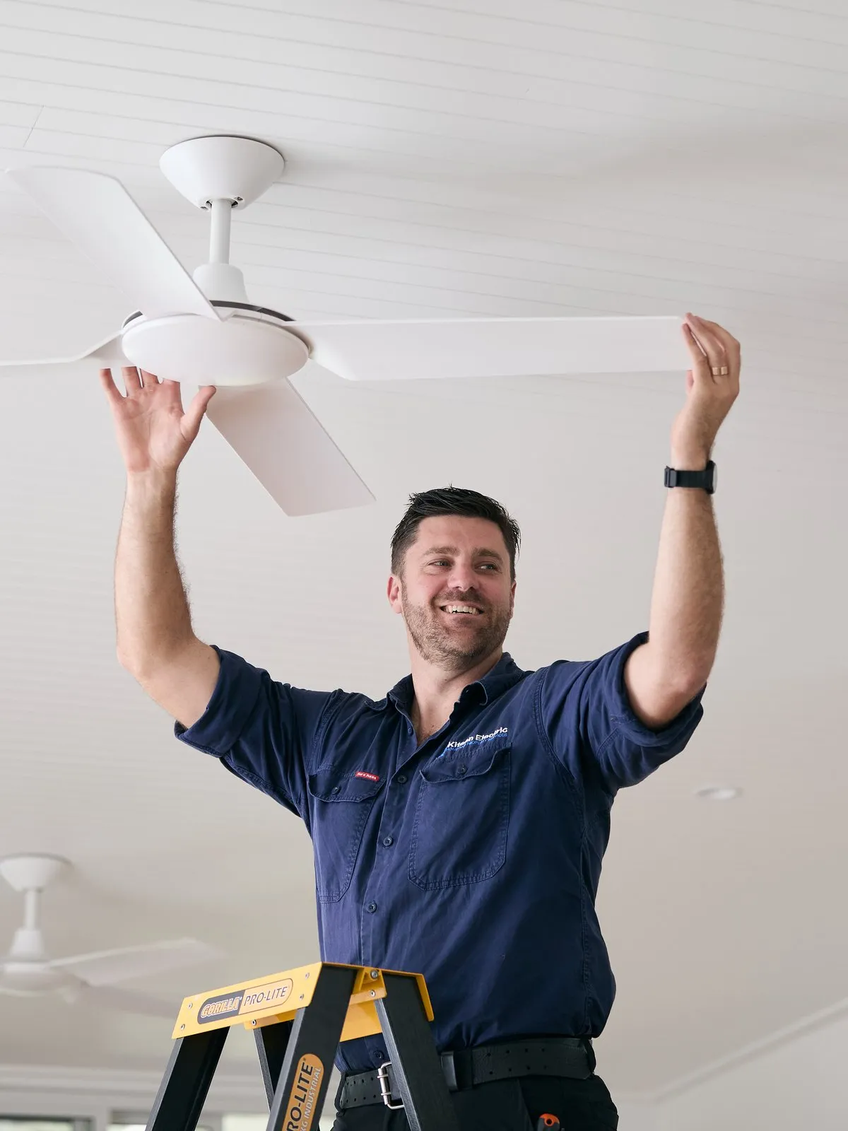 Anthony Kitson installing a ceiling fan in a Newcastle home