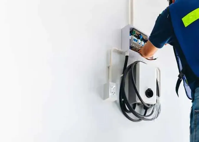 An electrician wiring a wall-mounted EV charger