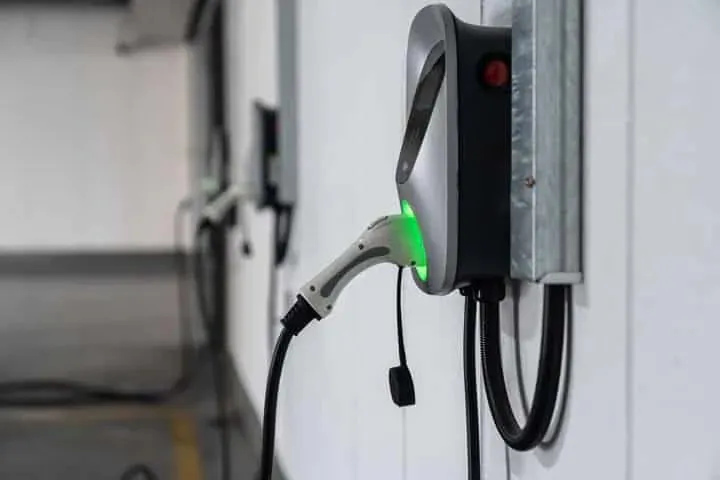 A wall-mounted EV charger with the cable plugged in