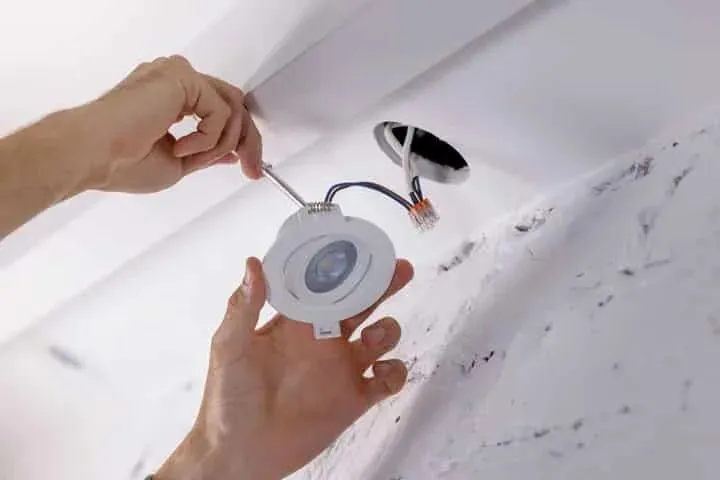 Hands wiring a ceiling light fitting