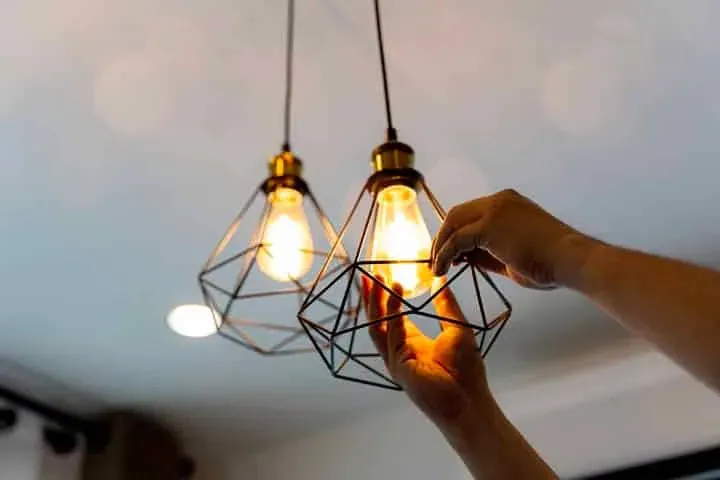 A hand fitting a pendant bulb
