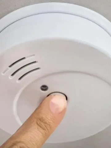 Pressing the test button on a smoke alarm