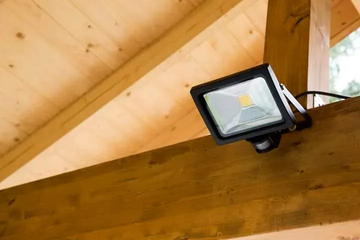 A sensor flood light mounted on a timber beam under the eaves